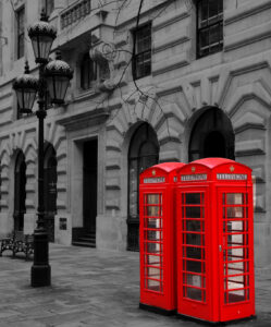 Two red telephone boxes in a monochrome background.